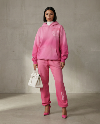 Person wearing a pink tracksuit with visible branding against a plain background