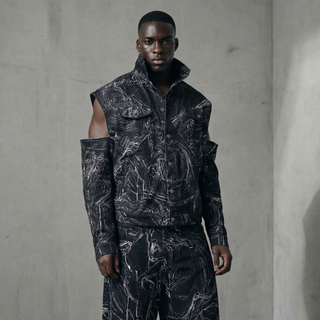 Man wearing a black and gray patterned outfit against a plain background