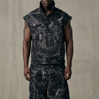 Man wearing a black sleeveless jacket and pants with intricate designs against a plain background