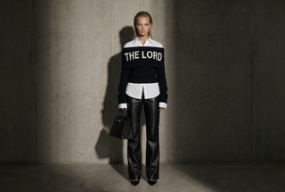 Person wearing a black and white outfit with 'THE LORD' text, standing against a plain background.