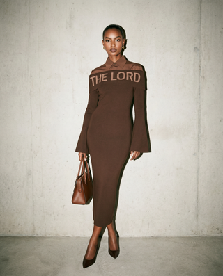 Woman wearing a brown dress with 'THE LORD' text against a plain background